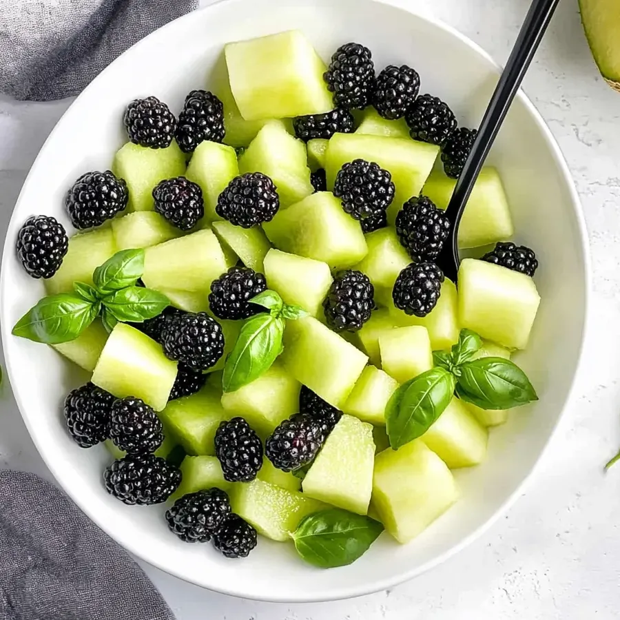 Eine Schüssel Fruchtsalat mit Brombeeren, Honigmelone und Basilikum.