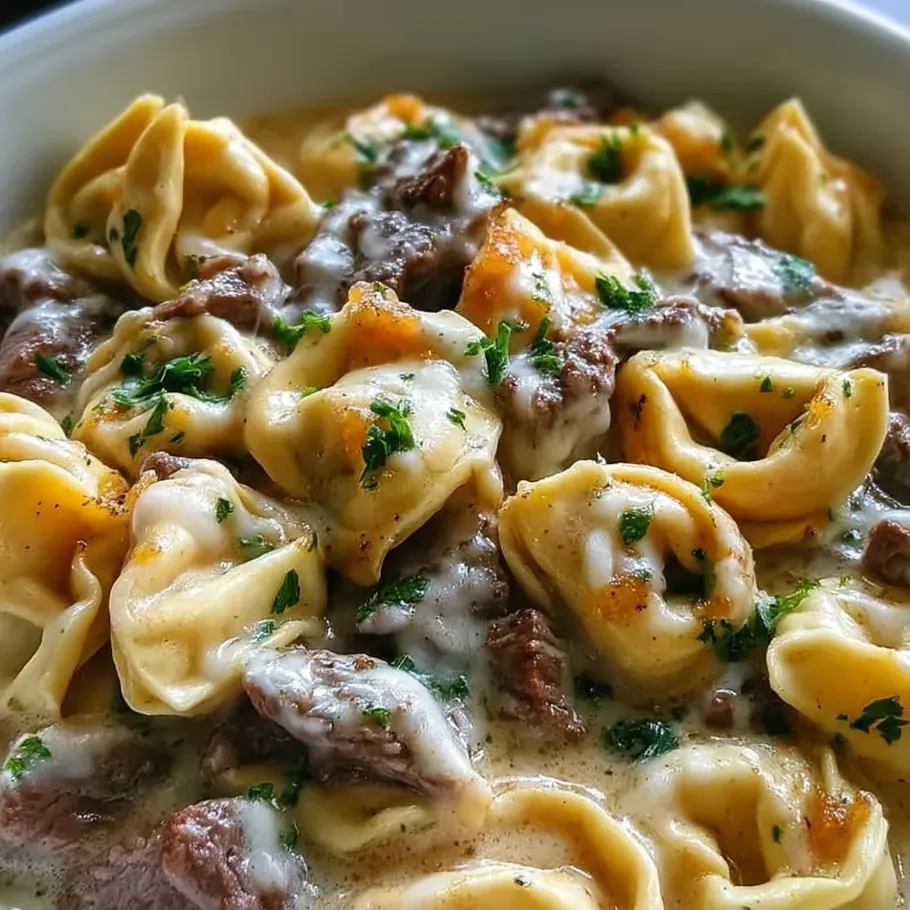 Eine Schüssel Tortellini mit Steak in cremiger Provolone-Soße.