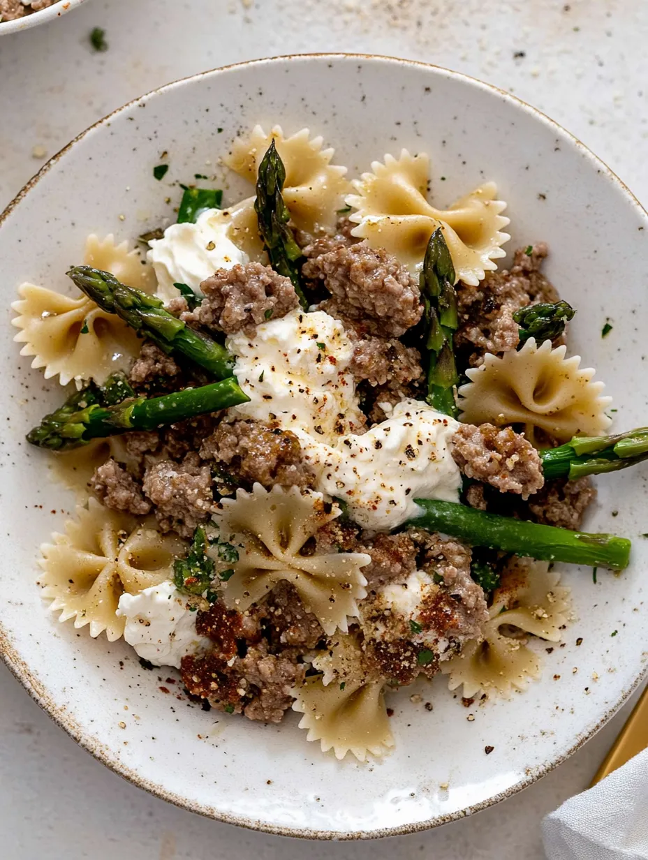 Eine Schüssel mit Pasta, Wurst und Spargel.