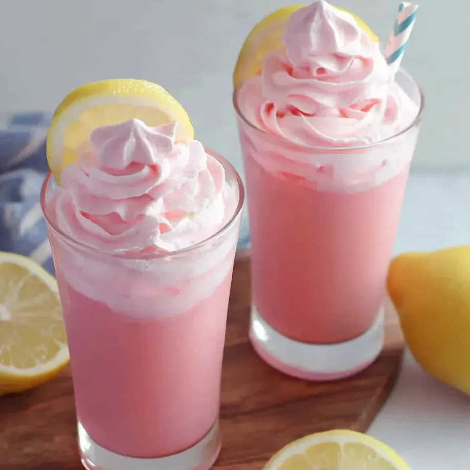 Zwei Gläser pinke Limonade mit Zitronenscheiben auf dem Tisch.