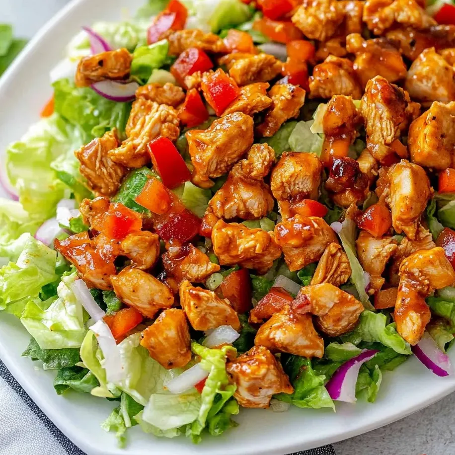 Ein Teller mit Hähnchensalat, dazu knackiger Salat und Tomaten.