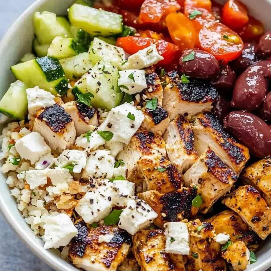 Eine Schüssel mit Huhn, Tomaten, Gurken und Oliven.