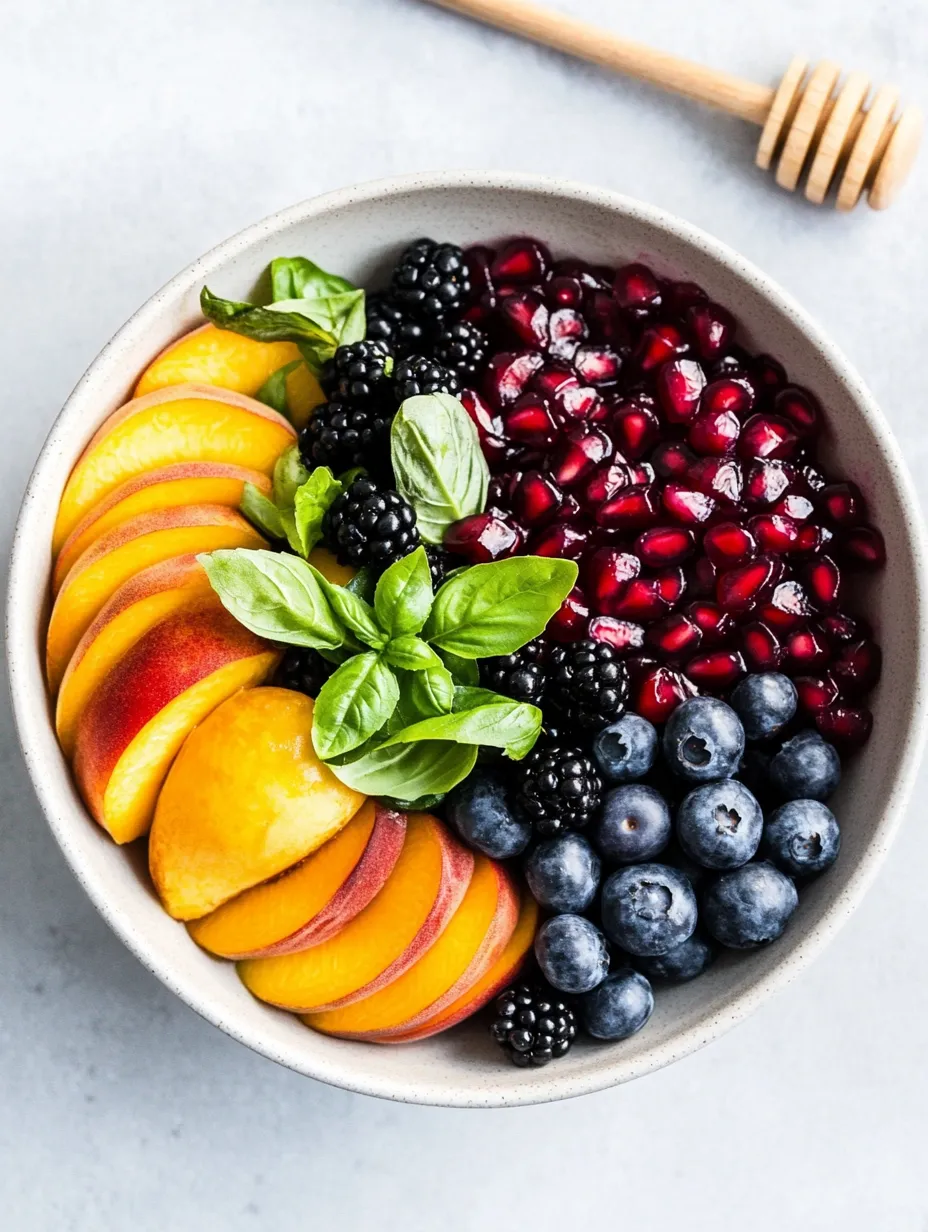Eine Schale bunter Früchte mit Blaubeeren, Himbeeren, Pfirsichen und Brombeeren.
