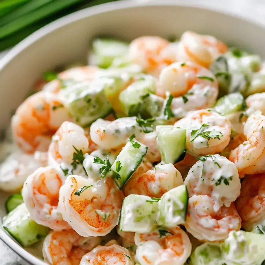 Eine Schale mit Garnelensalat, Gurkenstücken und anderem Gemüse.