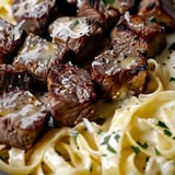Ein Teller mit Knoblauchbutter Steak Happen und cremigen Parmesan-Nudeln.