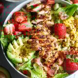 Eine Schüssel Hühnchensalat mit Erdbeeren, Mais und Salat.
