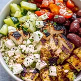 Eine Schüssel mit Huhn, Tomaten, Gurken und Oliven.