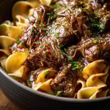 Eine Schüssel mit Pasta, Fleisch und Sauce.