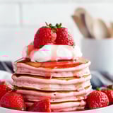 Ein Stapel Pfannkuchen mit frischen Erdbeeren obendrauf.