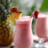 Ein Glas mit rosa Drink und einer Ananasecke obendrauf.