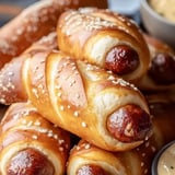 Ein Haufen Hot Dogs mit einer Schale Senf.