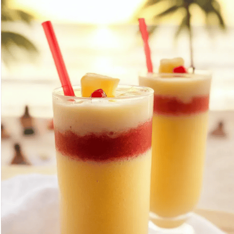 Zwei Gläser Ananassaft mit roten Strohhalmen.
