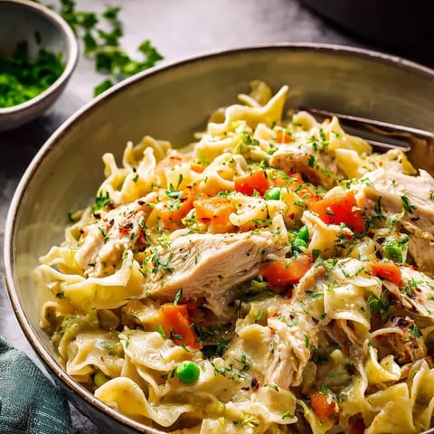Eine Schüssel Pasta mit Hähnchen und Gemüse.