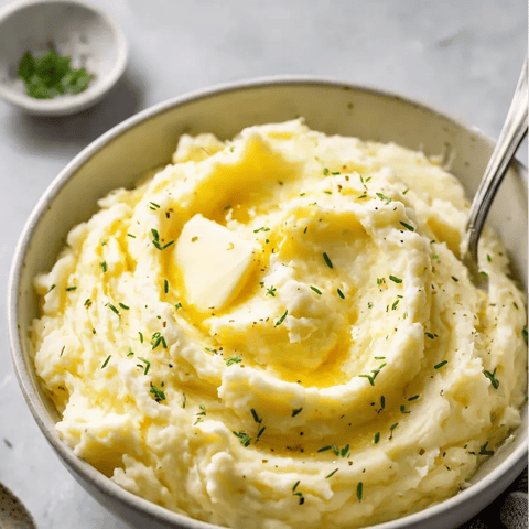 Ein Schüssel mit gegrilltem Fleisch und Kartoffeln.